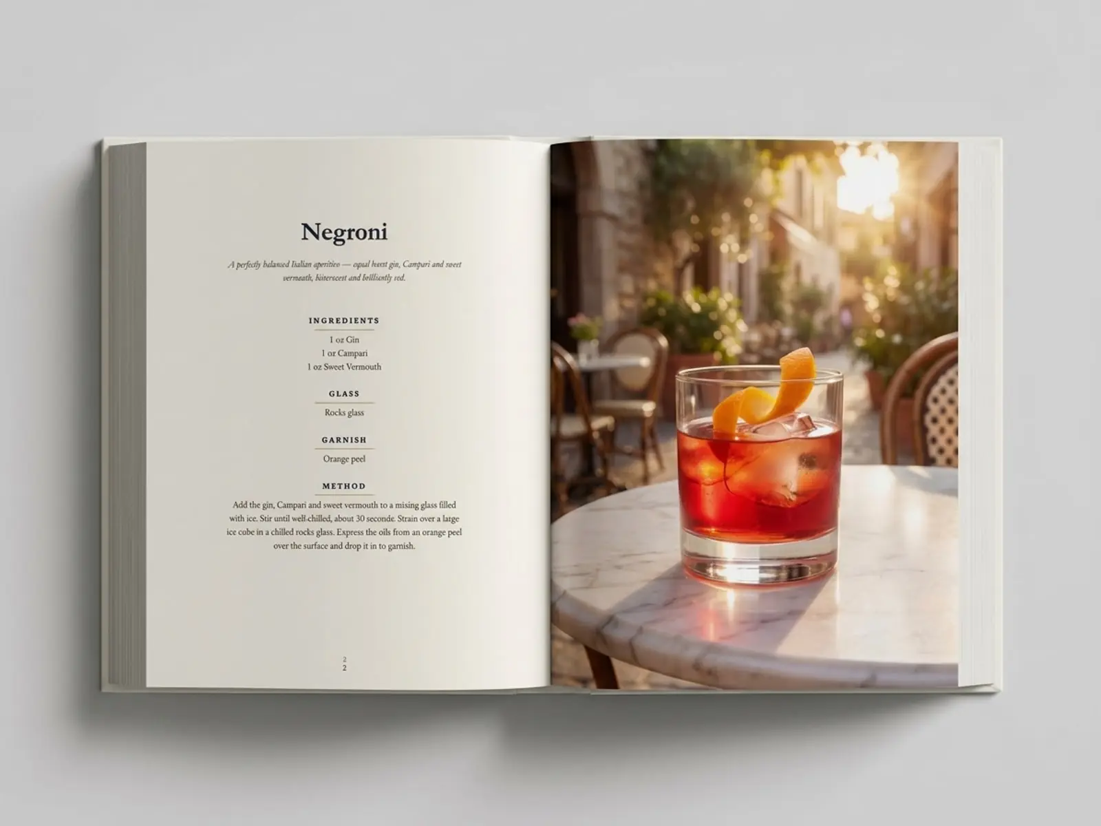 A real printed copy of Classic Cocktails lying open at the Negroni recipe and its photograph
